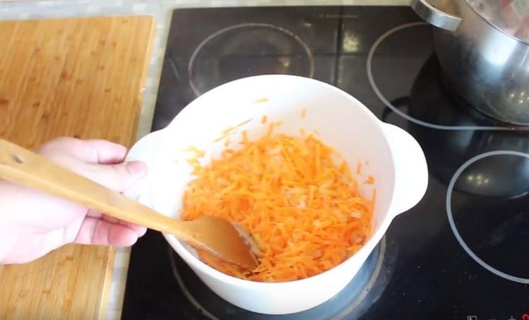 Fügen Sie Karotten der Zwiebel hinzu, kochen Sie alle zusammen für noch einige Minuten.