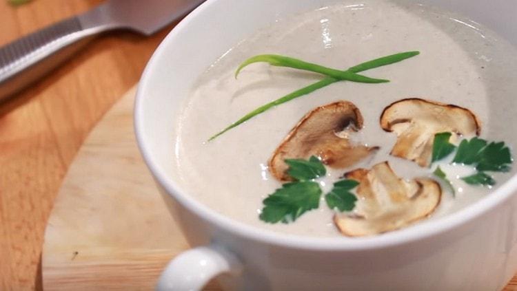 Ang sup na supa ng champignon na may cream, pinaglingkuran, nangunguna sa mga hiwa ng toasted kabute. pati na rin mga sprigs ng perehil.