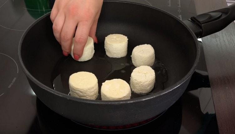 Ζεσταίνουμε το τηγάνι με φυτικό λάδι και απλώνουμε τα κέικ τυριού πάνω του.
