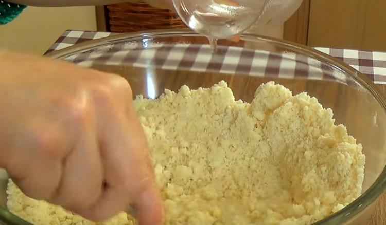 Versare acqua e aceto nella massa di farina e mescolare.