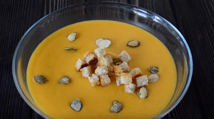 Una zuppa di crema di zucca preparata secondo la ricetta con crema può essere decorata con crostini e semi di zucca al momento di servire.