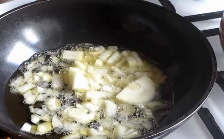 Friggi le cipolle per preparare la zuppa di formaggio con i funghi