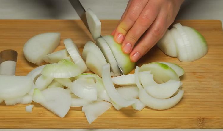 Zwiebeln hacken, um einen Gemüseeintopf mit Fleisch zuzubereiten