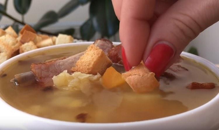La zuppa di piselli con costine affumicate viene solitamente servita con crostini.