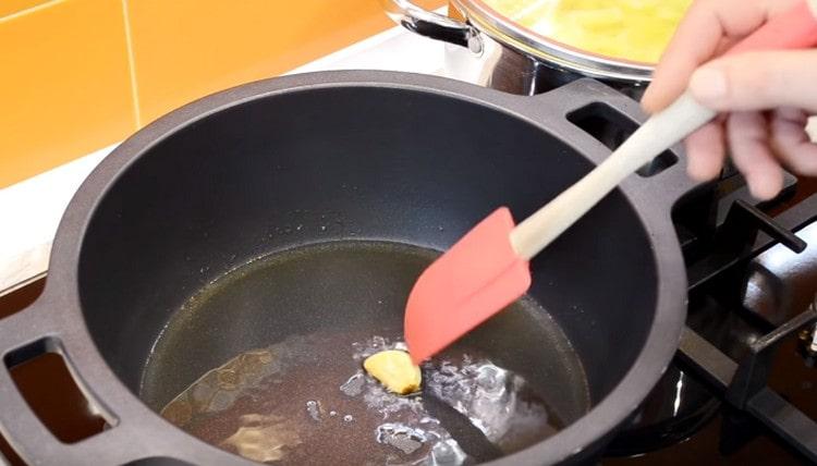 Ζεστάνετε το καζάνι ή το stewpan, ρίχνετε το φυτικό έλαιο και τηγανίζετε το σκελίδες σκόρδου.