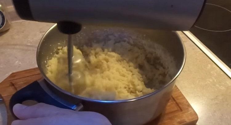 Fügen Sie Mehl zum kochenden Wasser hinzu und mischen Sie die Masse schnell mit einem Mixer, damit das Mehl gebraut wird.