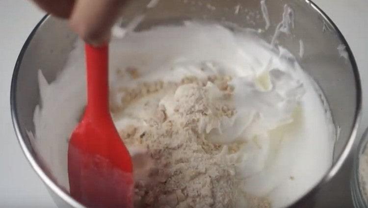На части добавяме орехово-брашнената маса в разбитите белтъци.
