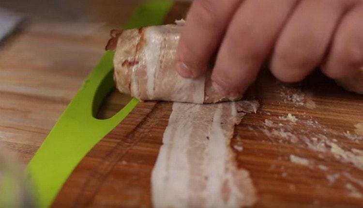 Avvolgere una cotoletta quasi finita in una sottile striscia di pancetta.