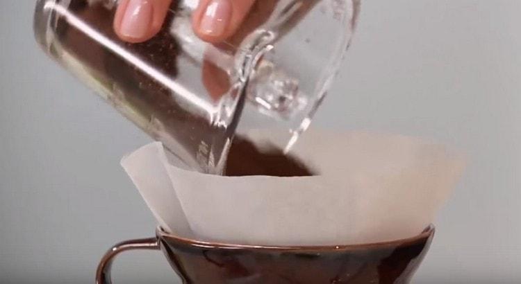 Gießen Sie gemahlenen Kaffee in den Filter und fügen Sie etwas kochendes Wasser hinzu.