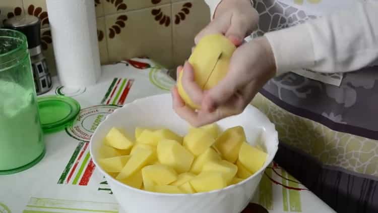 Um Hähnchenschenkel mit Kartoffeln im Ofen zu kochen, hacken Sie die Kartoffeln