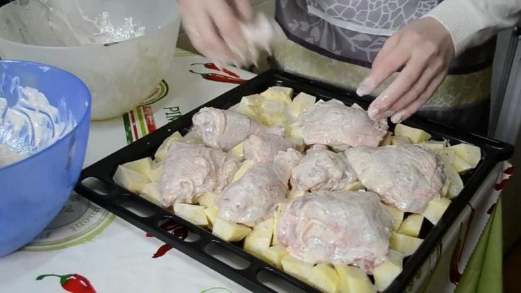 Um Hähnchenschenkel mit Kartoffeln im Ofen zu kochen, legen Sie die Zutaten auf ein Backblech