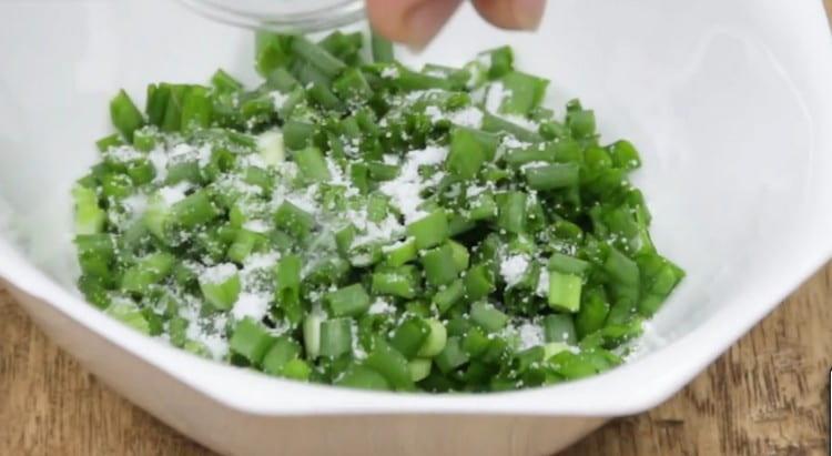 Смелете перата на зелен лук, добавете сол към тях.
