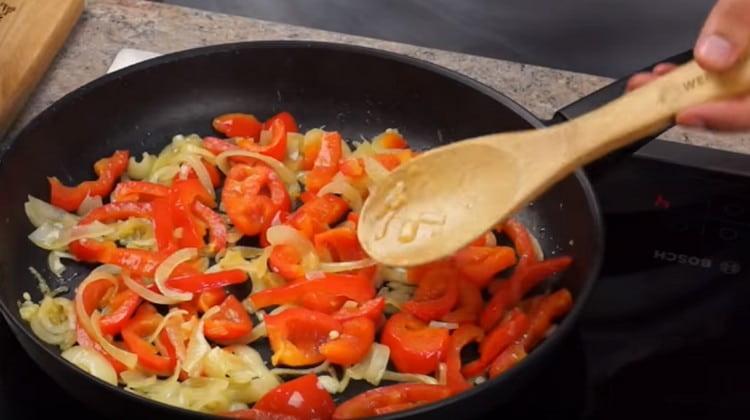 Csirke helyett a serpenyőben szétszórjuk a zöldségeket, és addig sütjük, amíg a hagyma átlátszóvá nem válik.