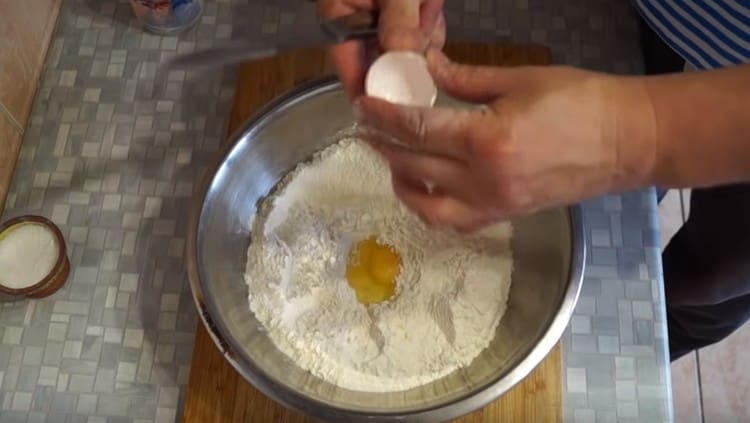 Wir schlagen das Ei in das Mehl.