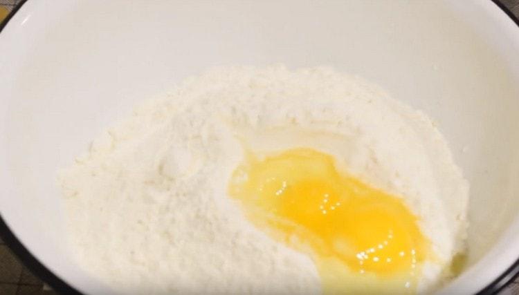 Разбиваме яйцата в брашното.