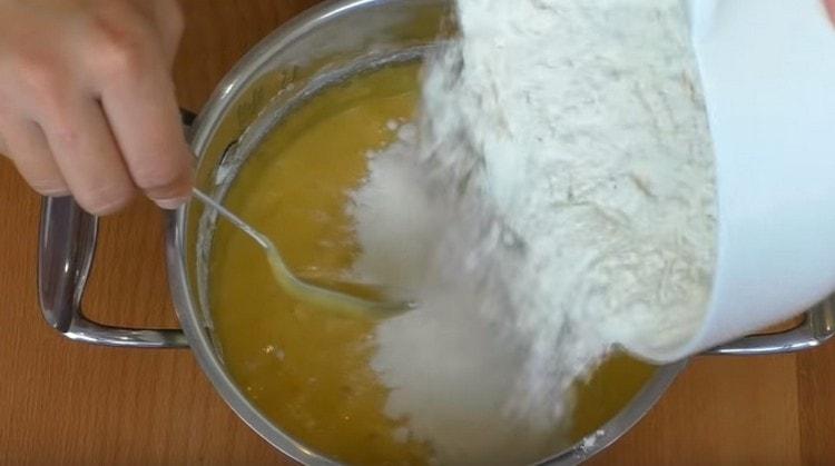 Wir geben nach und nach Mehl in die flüssige Masse und beginnen, den Teig zu kneten.