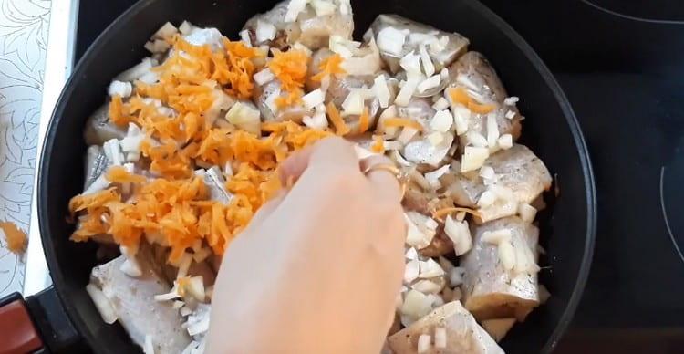 Mettiamo il pesce nella padella e sopra di esso cipolle e carote.