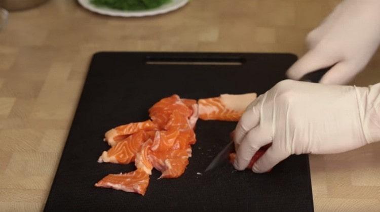 Нарежете червената риба на малки парченца.