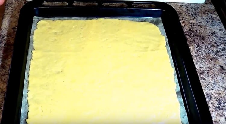 Lefedjük a sütőlapot pergamentel és húzzunk rá egy nagyobb darab tésztát.