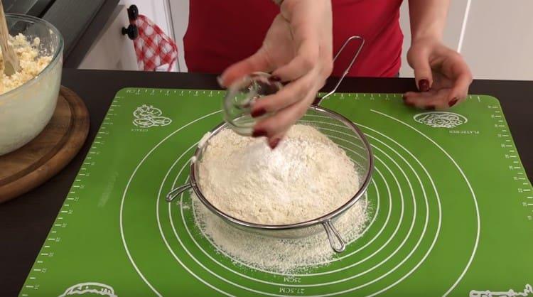 Setacciare la farina mescolata con il lievito sulla superficie di lavoro.