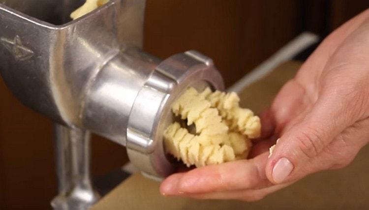 Разпределяме парче тесто в месомелачка и в резултат получаваме къдрави бисквитки.