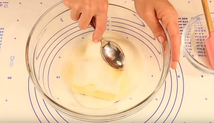 Fügen Sie der Butter Zucker hinzu und mahlen Sie die Masse mit einem Löffel.
