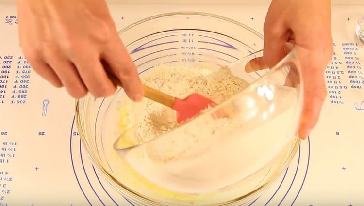 Fokozatosan adagoljuk be a lisztet egy sütőporral, és megkezdi a tészta dagasztását.