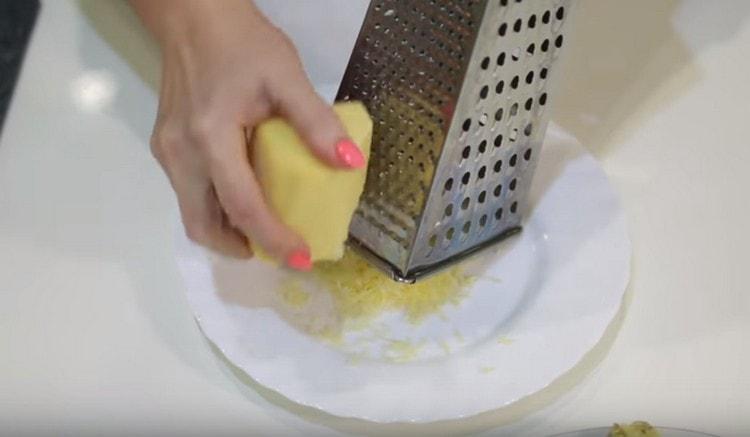 Su una grattugia fine strofiniamo il formaggio a pasta dura.