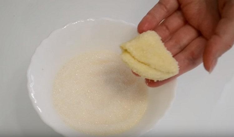 Потопете захарта от едната страна на триъгълниците от тестото, а другата поставете върху лист за печене.