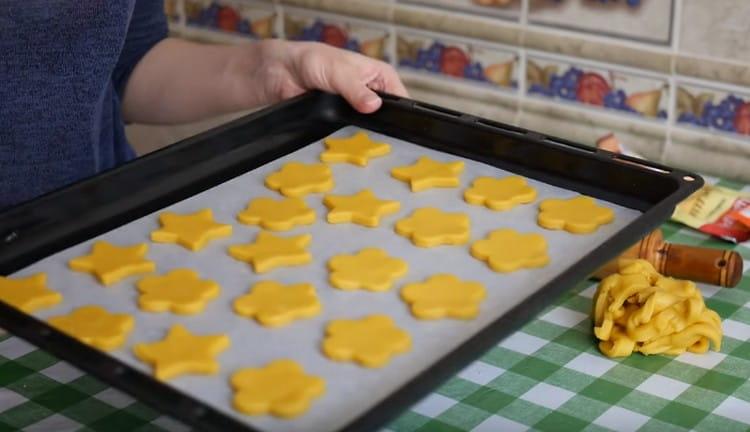 Wir breiten die Kekse auf einem mit Pergament bedeckten Backblech aus und schicken sie in den Ofen.