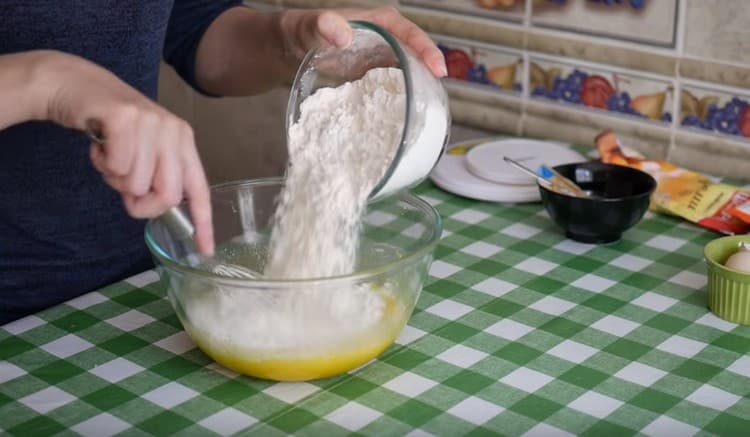 Fügen Sie nach und nach Mehl zu den flüssigen Bestandteilen hinzu und kneten Sie den Teig.
