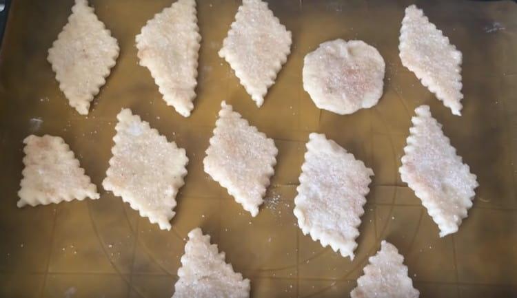 Разпределяме бисквитките върху хартия за печене, покрита с хартия за печене, след като потапяме всяко парче в смес от канела със захар.