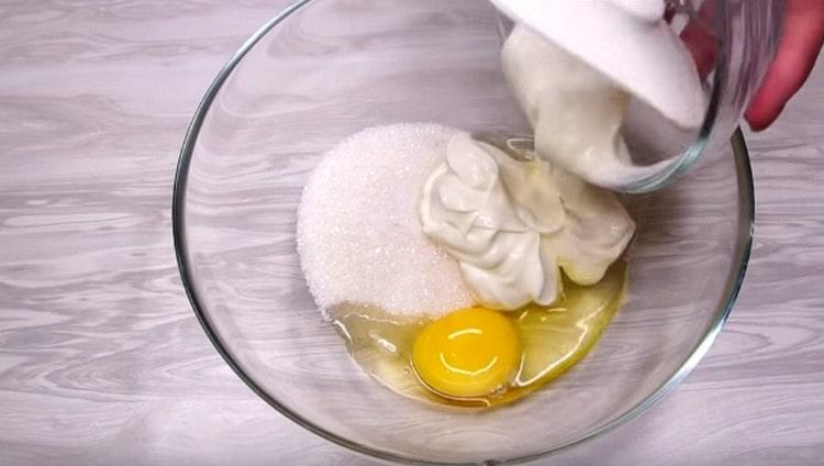Σε ένα άλλο μπολ, συνδέστε το αυγό. ξινή κρέμα, ζάχαρη και αλάτι.