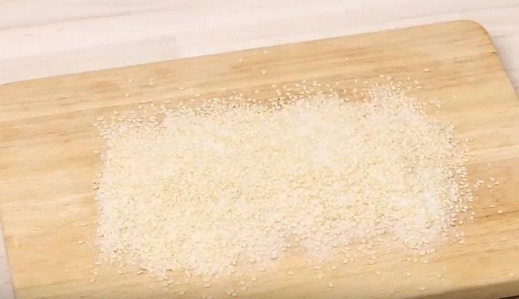 Versare una miscela di zucchero con semi di sesamo su una tavola, a livello.