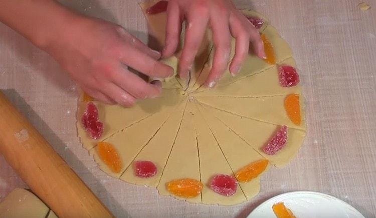 Alla base di ogni triangolo di pasta, metti un pezzo di marmellata e avvolgilo con un rotolo, formando un bagel.