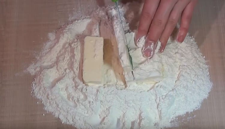 Разстиламе студено масло в брашно и го нарязваме на малки парченца с нож.