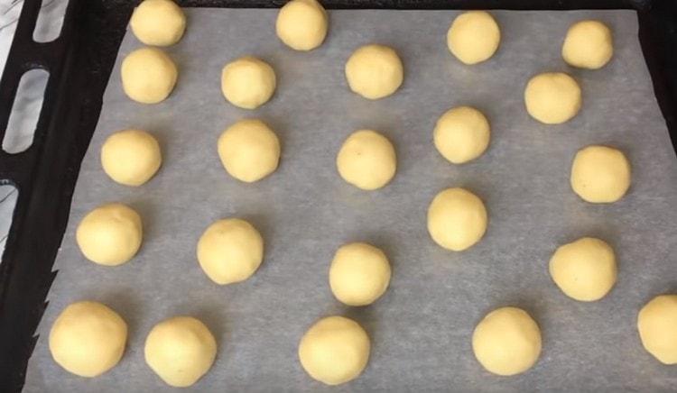 Поставете топките тесто с ядки вътре върху лист за печене и изпратете да се пекат във фурната.