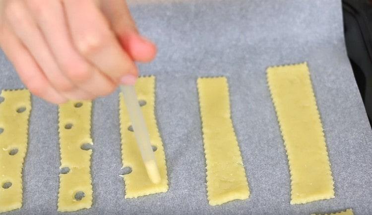 Ruošiniuose galite padaryti skylutes šiaudeliais, kad sausainiai primena sūrį.