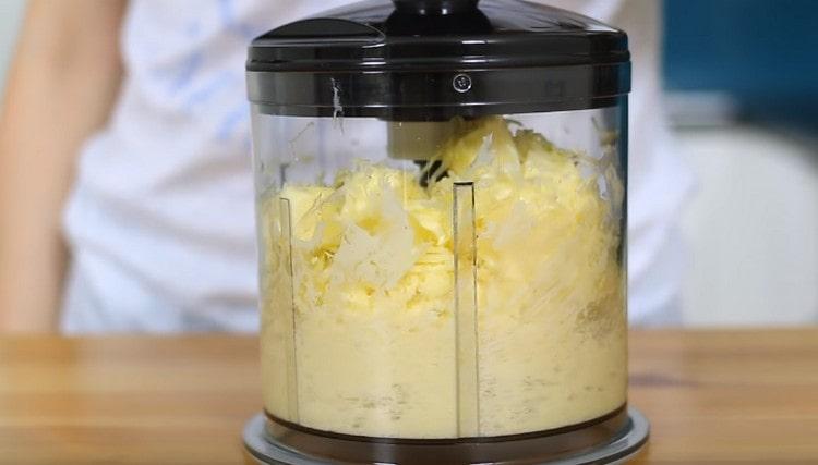 Wir unterbrechen Butter und Käse mit einem Mixer.