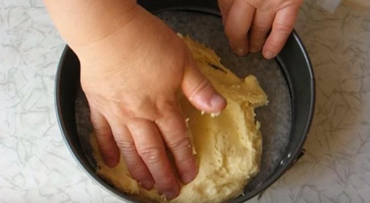 Nedves kézzel elosztjuk a tésztát egy sütőedénybe.