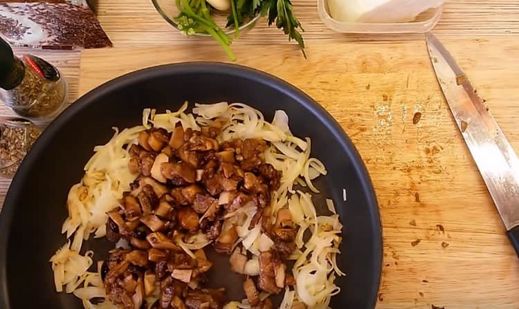 Κόψτε τα μανιτάρια σε κομμάτια και προσθέστε το κρεμμύδι στο τηγάνι.