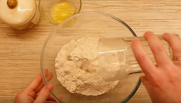 Versare la farina integrale in una ciotola, aggiungere acqua.