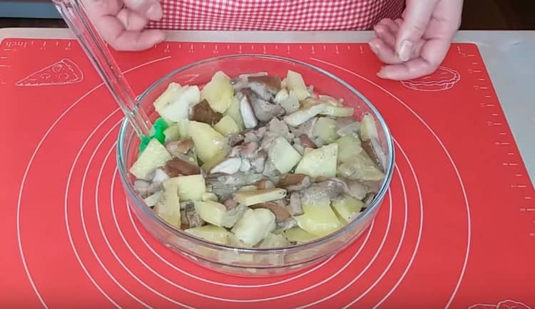 Rühren Sie die Kartoffeln mit dem Braten von Pilzen und Zwiebeln.