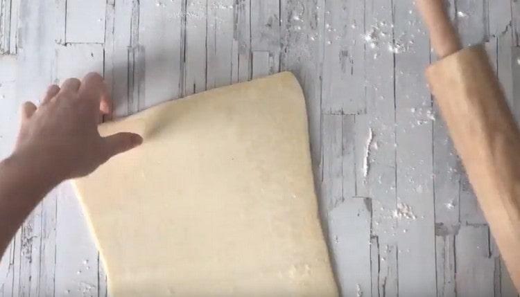 نخرج العجينة إلى حجم ورقة الخبز.