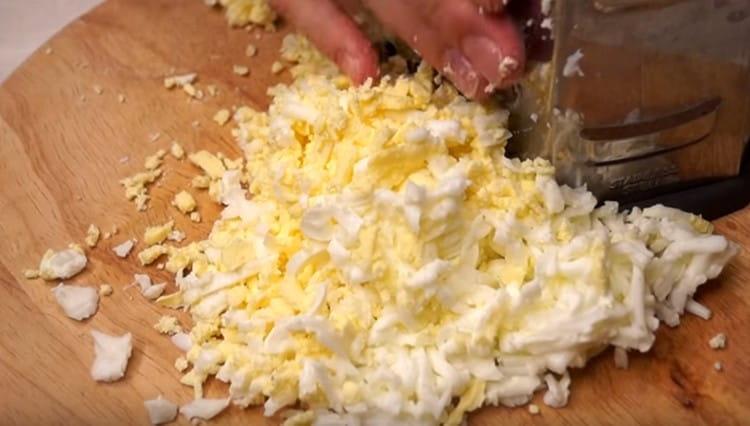 Su una grattugia grossa strofiniamo formaggio a pasta dura e uova.