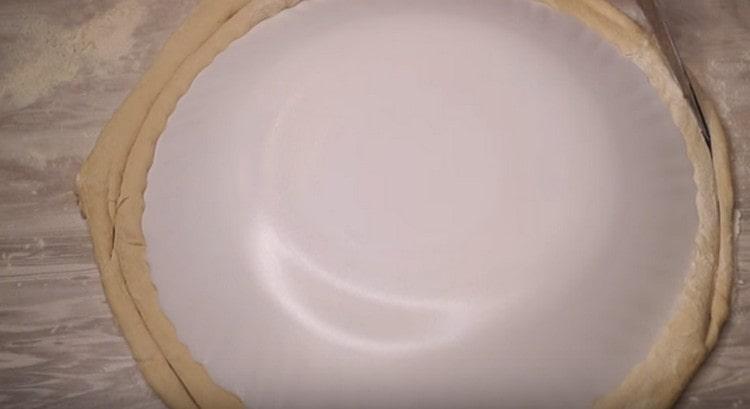 Βγάλτε τη ζύμη σε έναν αρκετά μεγάλο κύκλο και κόψτε ένα ομοιόμορφο σχήμα.