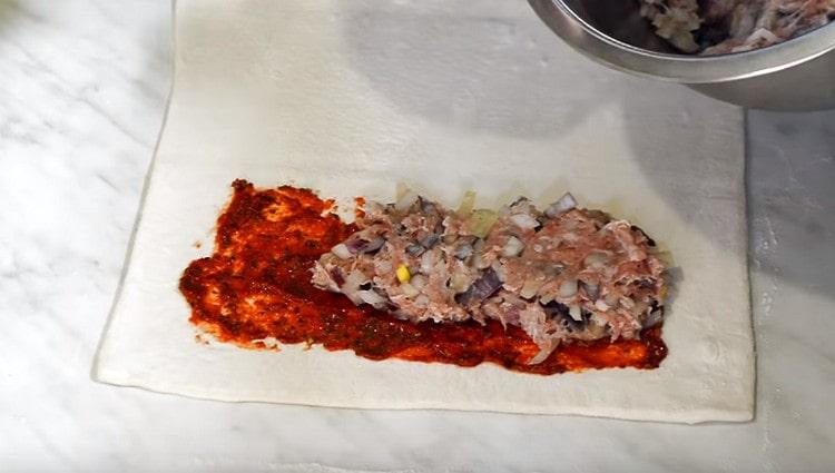 Lubrificare metà dell'impasto con salsa e distribuire la carne macinata.