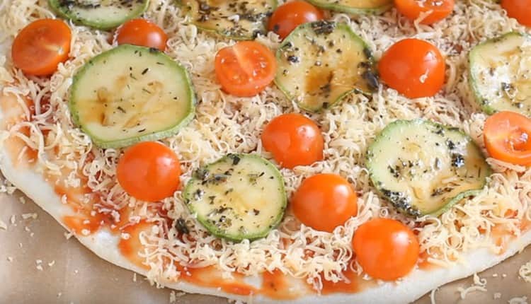 Auf Käse verteilen wir Kreise aus Zucchini und Kirschtomaten.