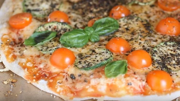 Valmis kasvissyöjä pizza voidaan koristaa basilikanlehdillä.