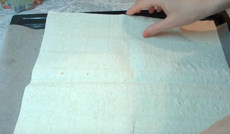 Kumakalat kami sa isang baking sheet isang sheet ng tinapay na pita.